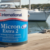 Can of International Micron Extra 2 antifouling paint on a dock with boats in the background