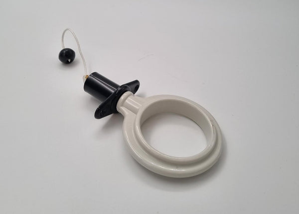 White circular object with a black cap on a light gray background