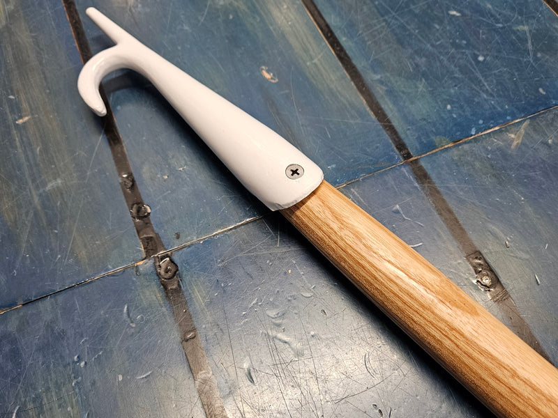 White hook with wooden handle on a metal surface