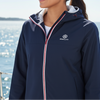 Woman wearing a navy jacket with a logo on a boat with water in the background