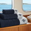Stack of navy and white towels with a star design on a wooden surface with ocean view