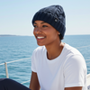 Woman wearing a blue knit beanie and white shirt on a boat with ocean in the background