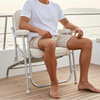 Man sitting on a chair on a boat deck with water and sky in the background