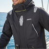 Man wearing a black Musto jacket on a boat with blue water and clear sky in the background