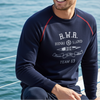 Man wearing a navy blue sweatshirt with visible branding on a boat with ocean in the background