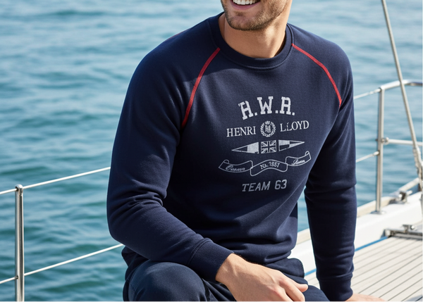 Man wearing a navy blue sweatshirt with visible branding on a boat with ocean in the background