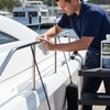 Man cleaning a boat with a bottle of cleaner on a dock.