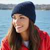 Woman wearing a red jacket and navy beanie on a boat with water in the background