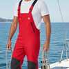 Man wearing red overalls on a boat with blue water and sky in the background
