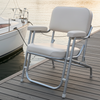 Two white chairs on a dock with boats in the background