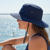 Woman wearing a blue bucket hat on a boat with water in the background