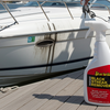 Person holding a bottle of Starbrite Black Streak Remover next to a boat on a dock.