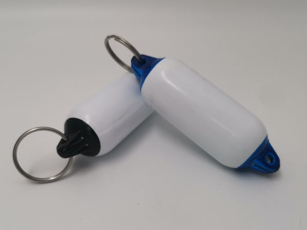 Two white and blue keychain fobs with metal rings on a light gray background
