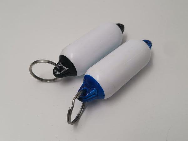 Two white and blue cylindrical keychain items with metal rings on a light gray background