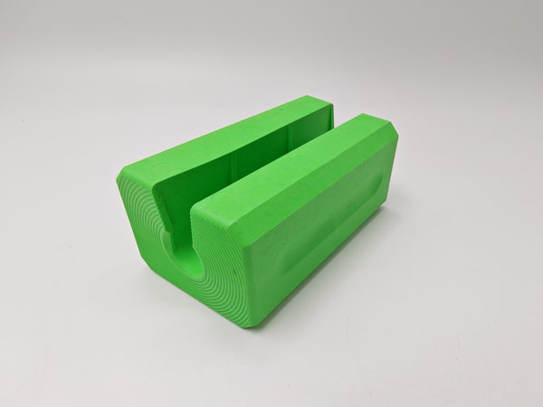 A bright green 3D-printed U-shaped block with a textured, layered appearance, shown on a neutral light gray background.