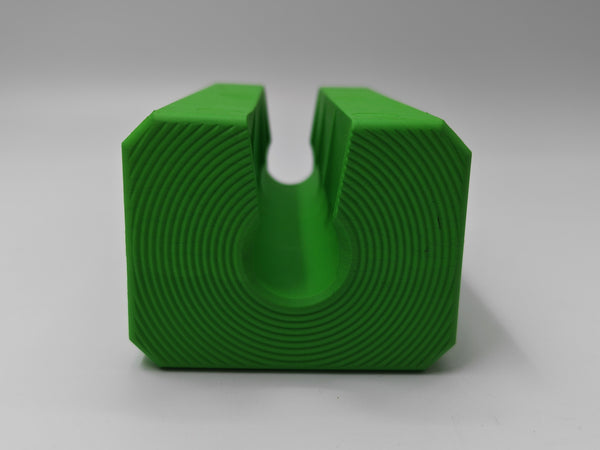 A bright green 3D-printed U-shaped block with concentric circular layer lines, shown on a neutral gray background.