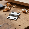 Metal hinge on a wooden surface with woodworking tools and wood shavings.