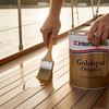 Person applying International Goldspar Original wood finish to a boat deck with sunset in the background.