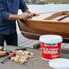 Man working on a wooden boat with NORSKI glue powder aerosil container by a lake.