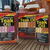 Three bottles of teak oil on a wooden deck with a boat in the background.