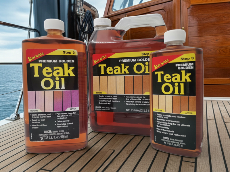 Three bottles of teak oil on a wooden deck with a boat in the background.