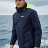 Man wearing a navy jacket with a yellow hood on a boat with ocean and cloudy sky in the background