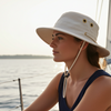 Woman wearing a wide-brimmed hat on a boat with water in the background