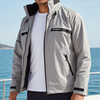 Man wearing a gray jacket on a boat with ocean and sky in the background