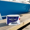 Can of Ancillary Products paint on a dock with a blue sailboat in the background