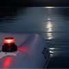 Boat with a red light on a lake at night under a full moon