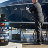 Person washing a boat with a bottle of Marine Boat Wash Shampoo in the foreground.