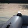 Inflatable boat on a lake with a light on during sunset