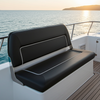 Black cushioned bench on a boat deck with ocean and sunset in the background
