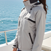 Woman wearing a gray jacket on a boat with ocean in the background