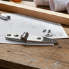 Woodworking tools and materials on a wooden table with blueprints in the background.