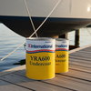 Two cans of International YRA600 Undercoat on a dock with a sailboat in the background.
