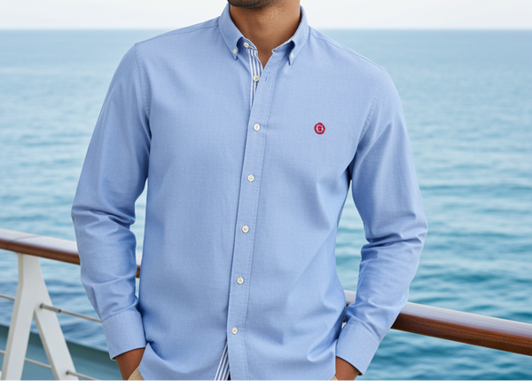 Man wearing a light blue shirt with a red logo on a boat with ocean view