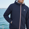 Man wearing a navy jacket with a brand logo on a boat with water and sky in the background
