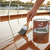 Person applying Alfex Timbercote varnish to a boat deck with a brush.
