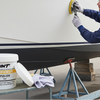 Person polishing a boat with a container of Grunt Supawax Polish nearby.