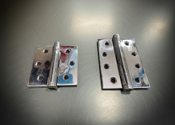 Two metallic hinges on a reflective surface