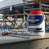 Can of Regatta additive on a table with a boat in the background